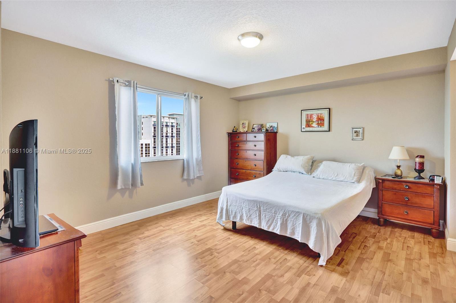 A bedroom features light-colored walls, wood flooring, a bed, a dresser, and a window — 816 NW 11th St # 905, Miami FL 33136, MIAMI, FL