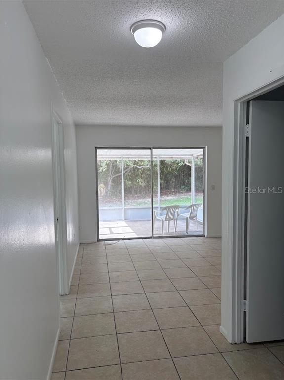 A room with tiled floors leads to a screened-in patio through sliding glass doors — 7467 MEAD DRIVE, SPRING HILL, FL