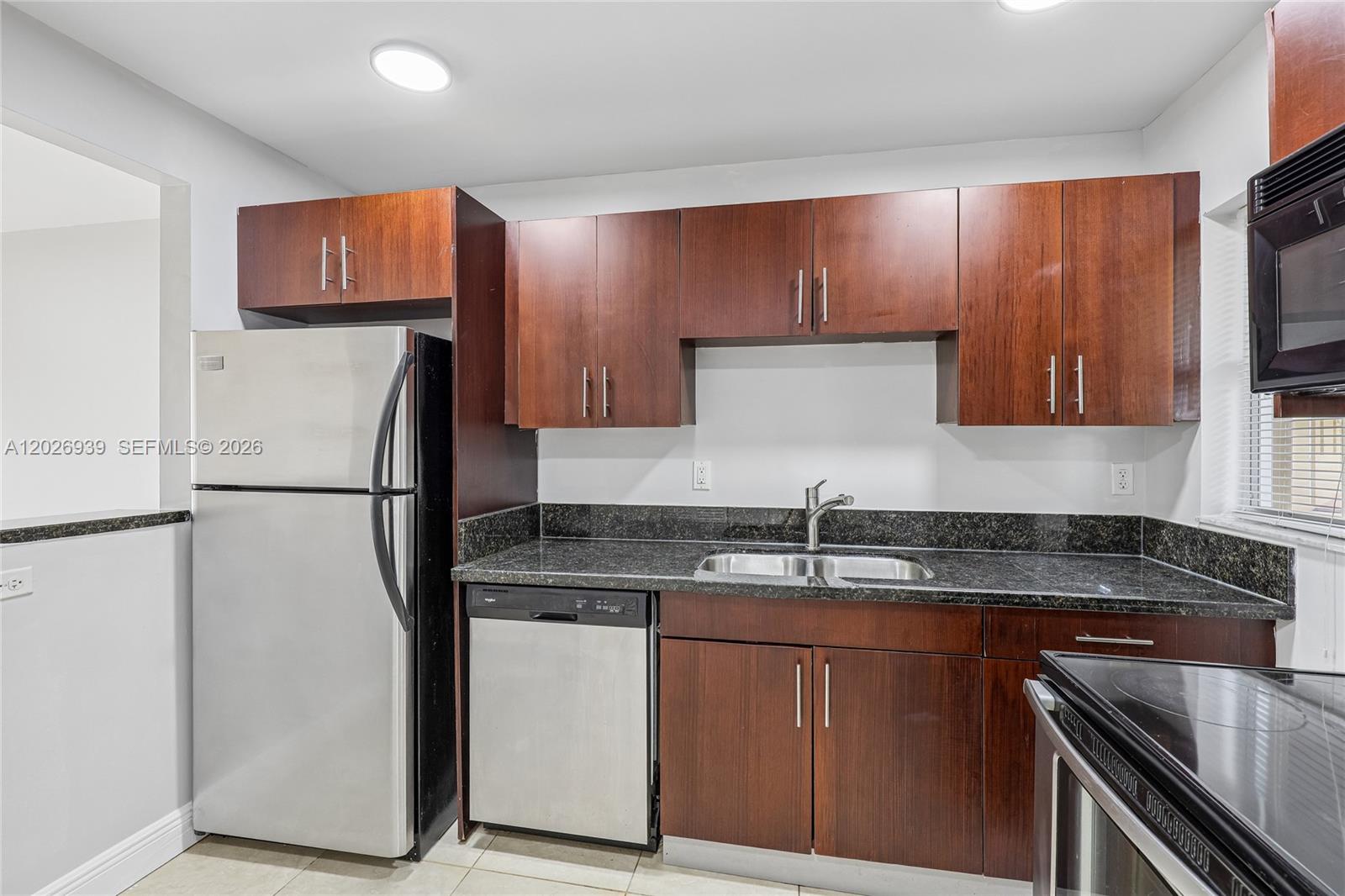 A kitchen features dark wood cabinets, stainless steel appliances, and black granite countertops — 4147 Stirling Rd # 504, Dania Beach FL 33314, DANIA BEACH, FL
