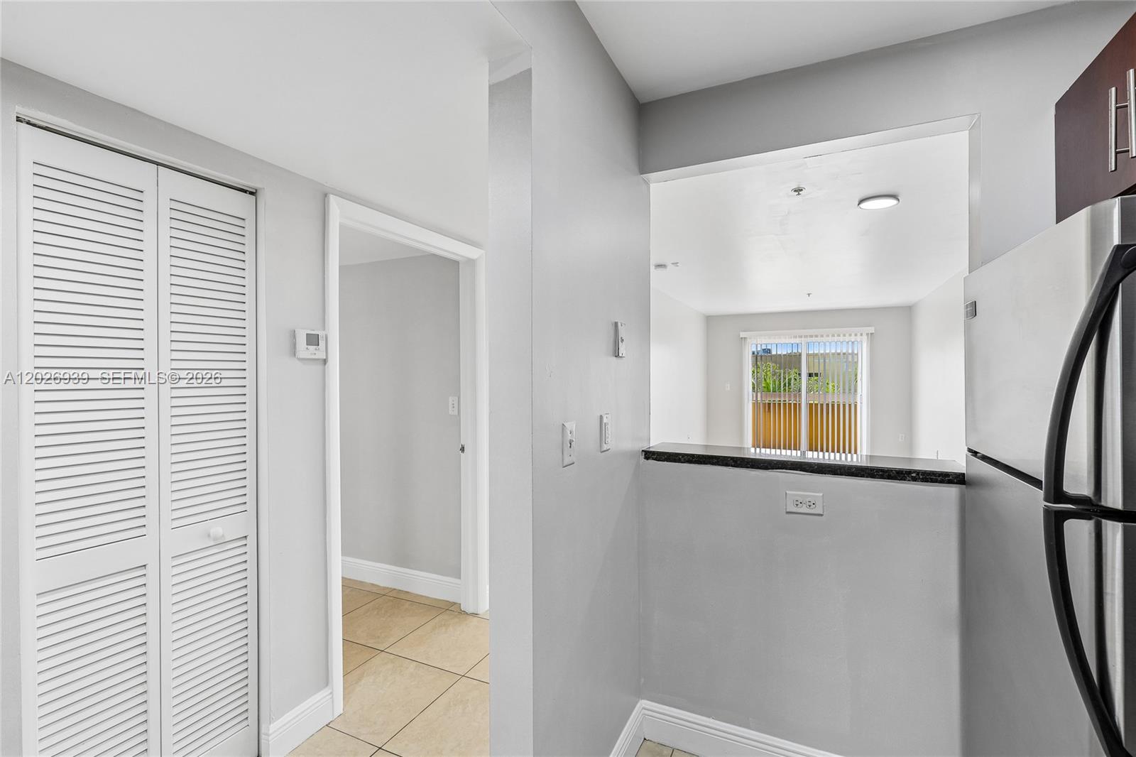 A kitchen pass-through window overlooks a living area with a sliding glass door — 4147 Stirling Rd # 504, Dania Beach FL 33314, DANIA BEACH, FL