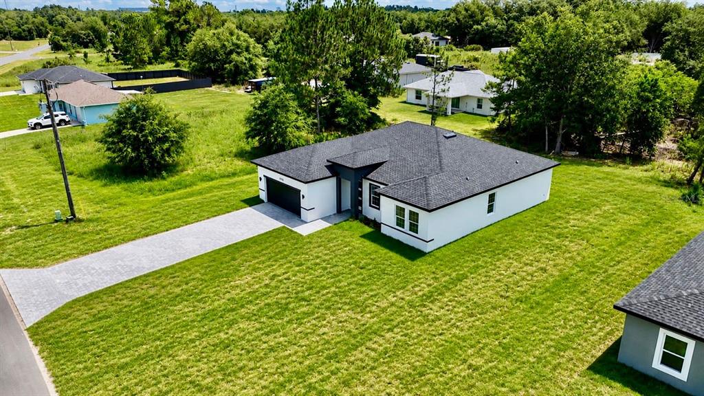 An aerial view shows a modern white house with a dark roof and paved driveway — 15775 SW 59TH AVENUE ROAD, OCALA, FL