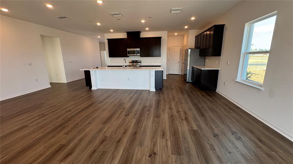 A kitchen with dark cabinets, a white island, and wood-look flooring in an open space — 857 HAWTHORNE BERRY ROAD, LAKELAND, FL
