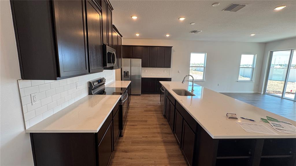 A kitchen features dark wood cabinets, white quartz countertops, a subway tile backsplash, and appliances — 857 HAWTHORNE BERRY ROAD, LAKELAND, FL