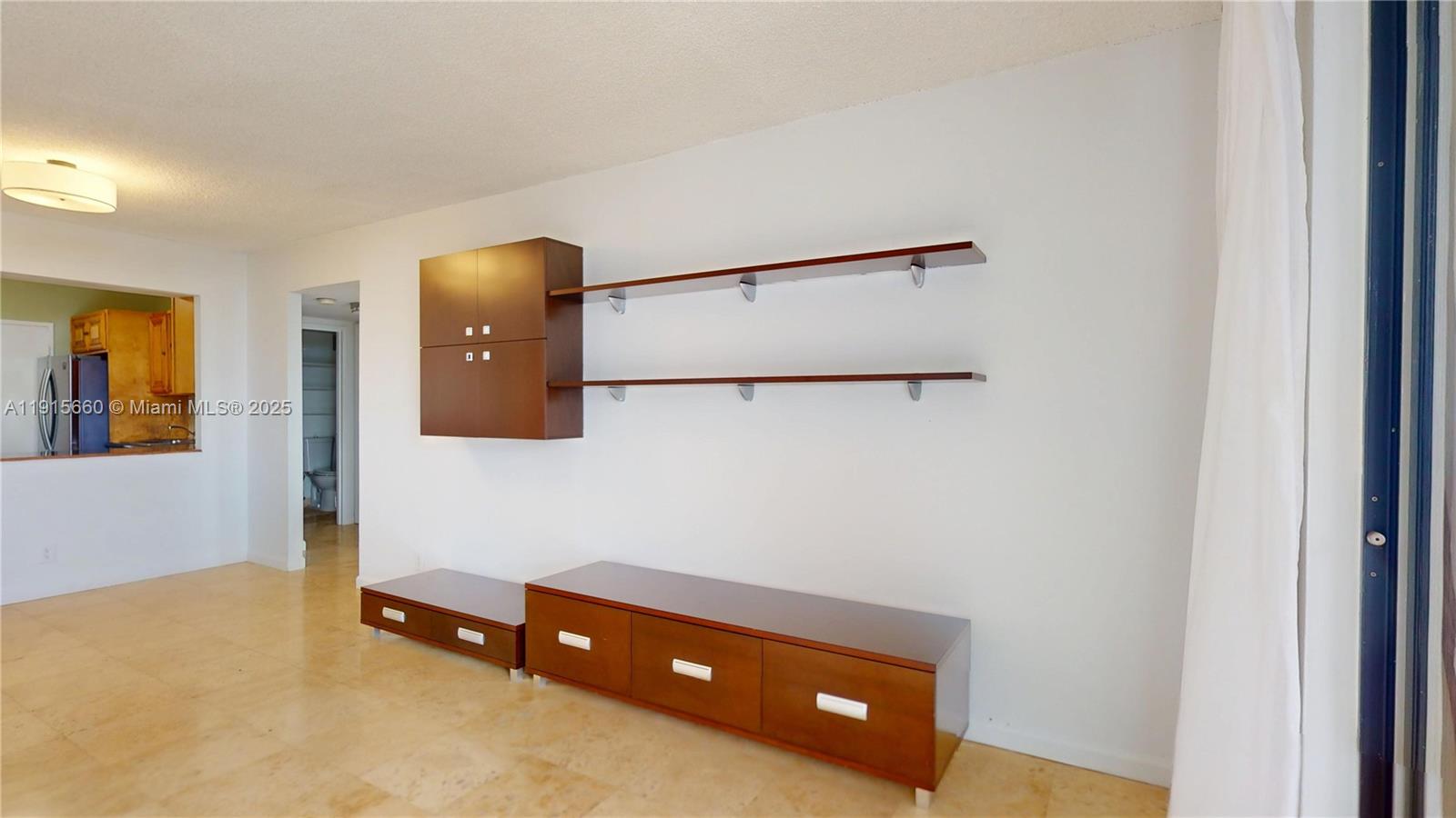 A living room features a wall-mounted storage unit, floating shelves, and low wooden cabinets — 500 Three Islands Blvd # 408, Hallandale Beach FL 33009, HALLANDALE BEACH, FL