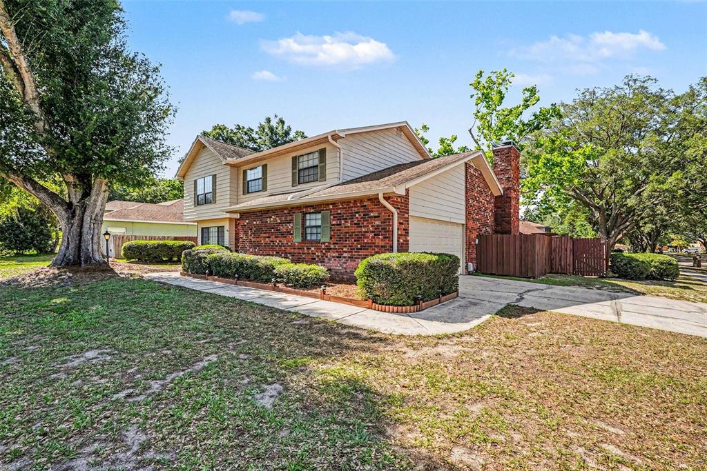 A two-story brick and siding house features a chimney, garage, and a large front yard — 6612 PEACHTREE DRIVE, TAMPA, FL