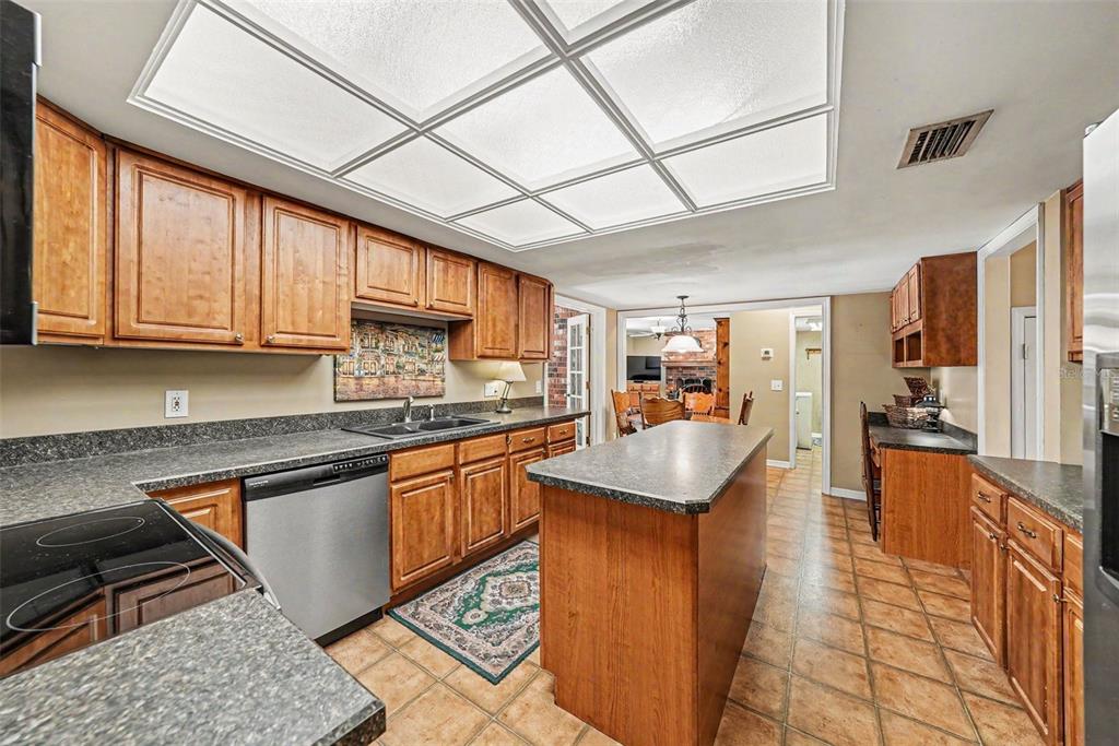 A kitchen with wood cabinets, dark countertops, a central island, and a grid ceiling light — 6612 PEACHTREE DRIVE, TAMPA, FL