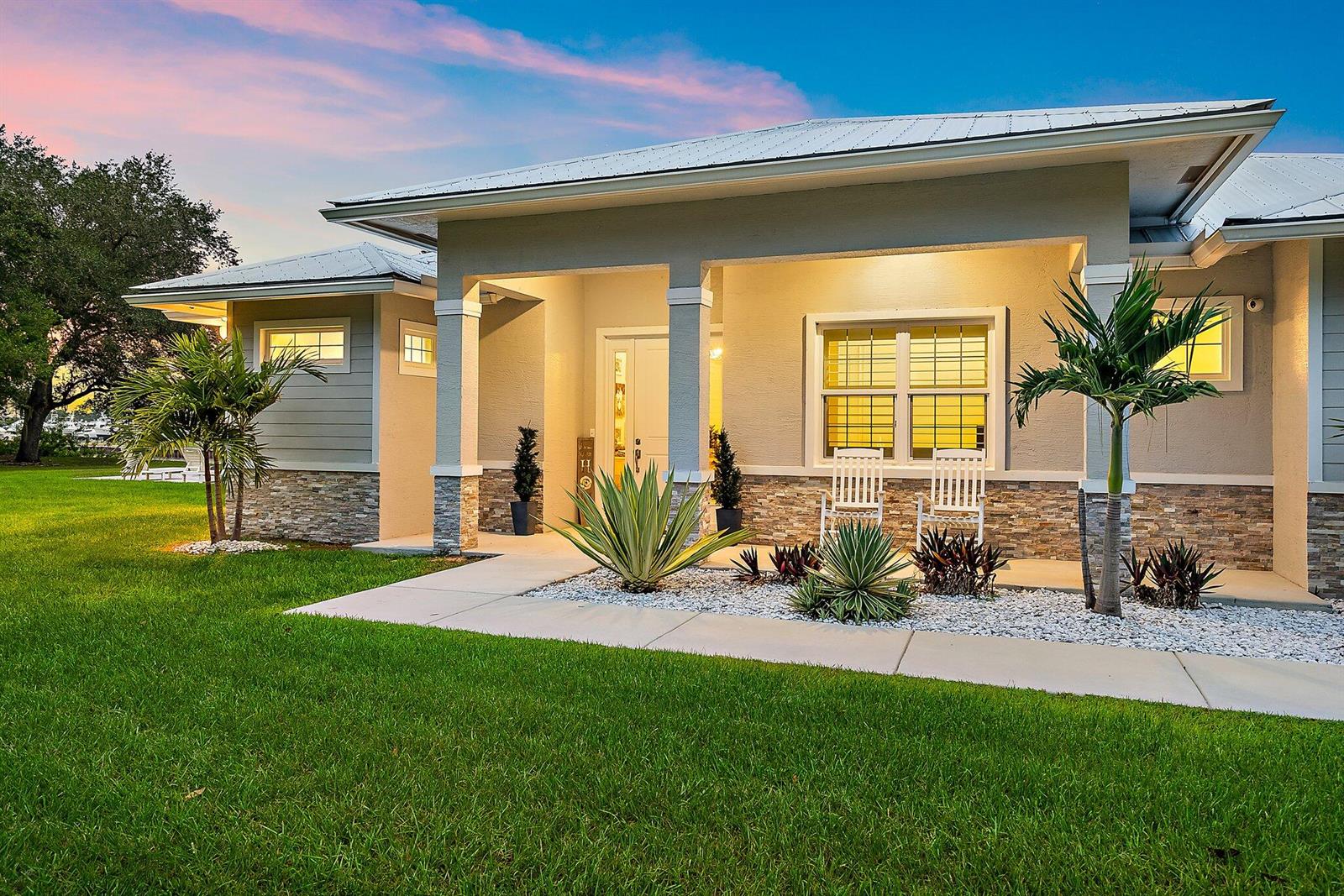 A single-story house exterior features a covered porch, stone veneer, and a manicured lawn — 12955 SW Kanner Highway, FL 34956, FL