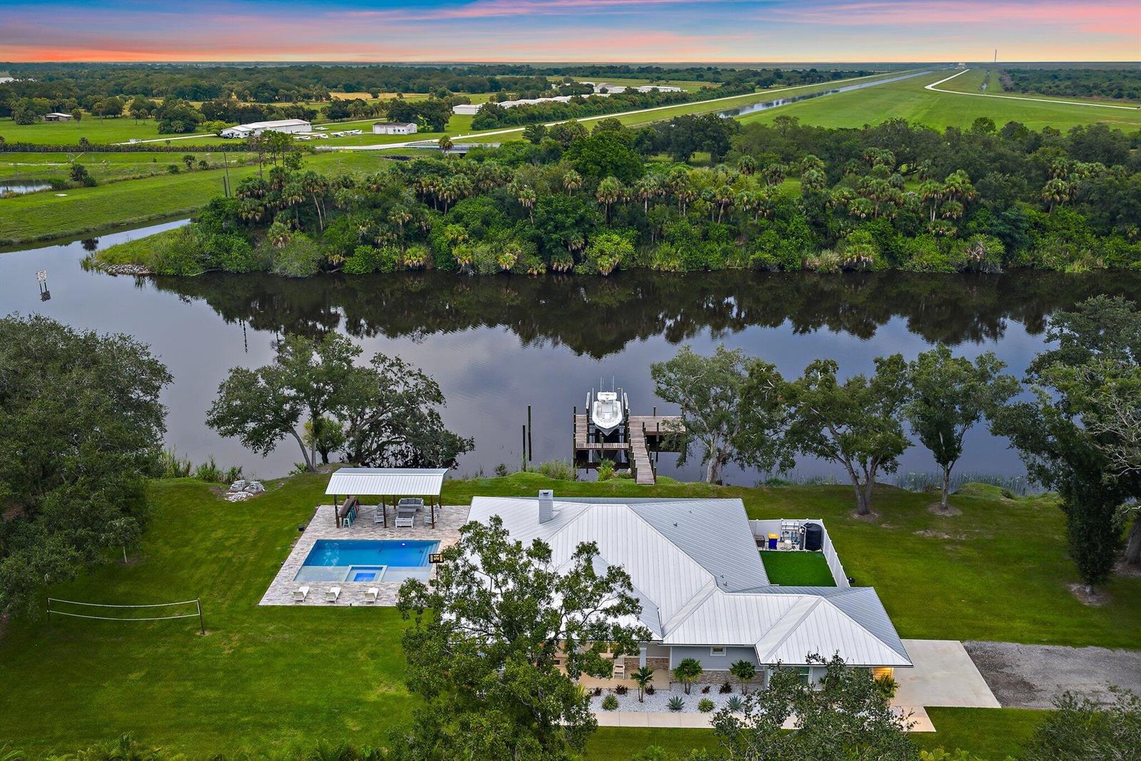 An aerial view of a house with a pool, covered patio, and private boat dock — 12955 SW Kanner Highway, FL 34956, FL