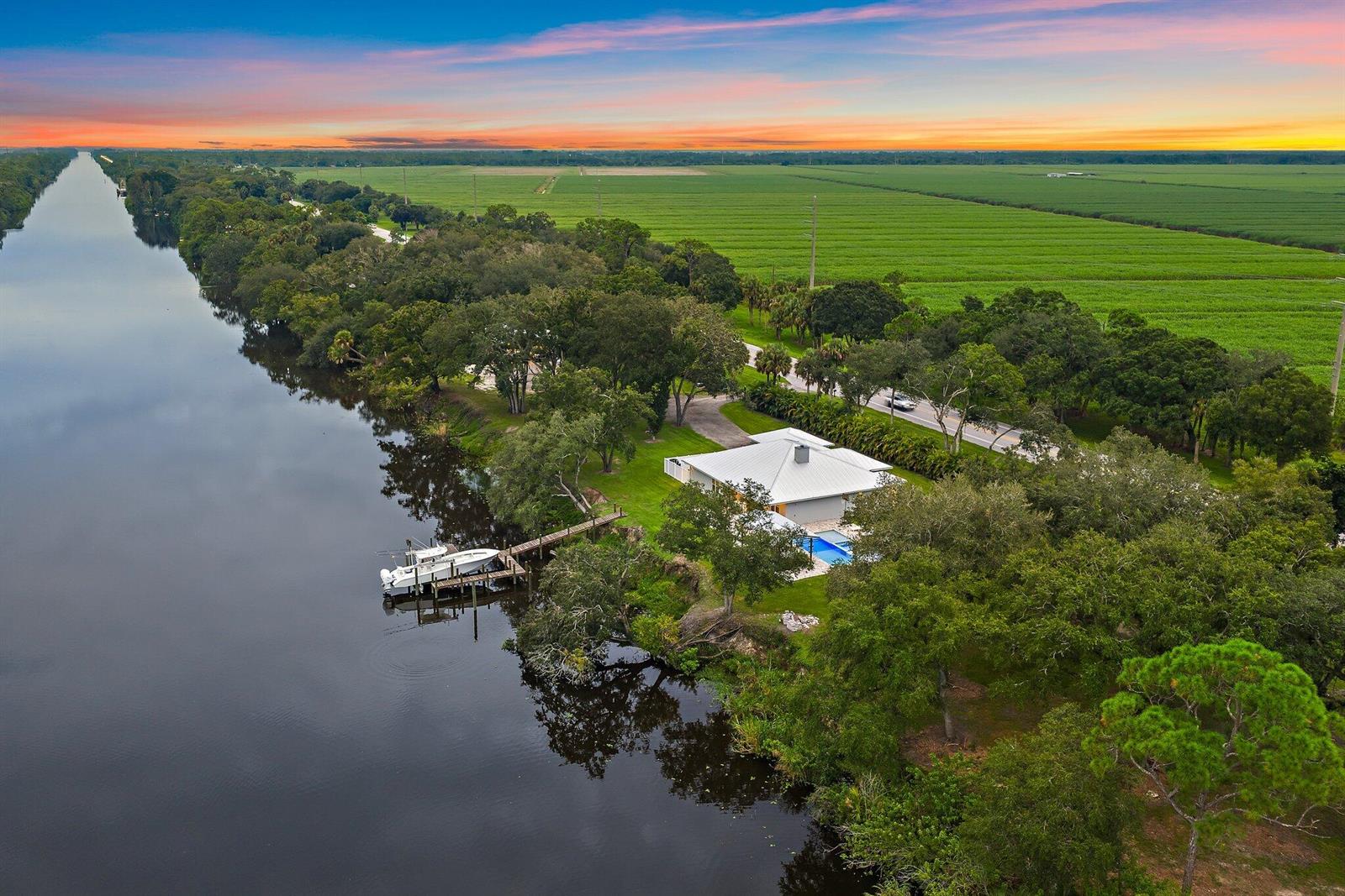 An aerial view shows a house with a pool and dock along a canal — 12955 SW Kanner Highway, FL 34956, FL