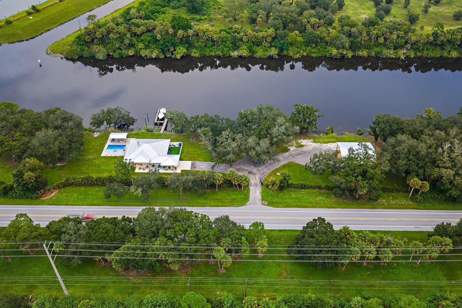 An aerial view shows a house with a pool and dock along a river — 12955 SW Kanner Highway, FL 34956, FL