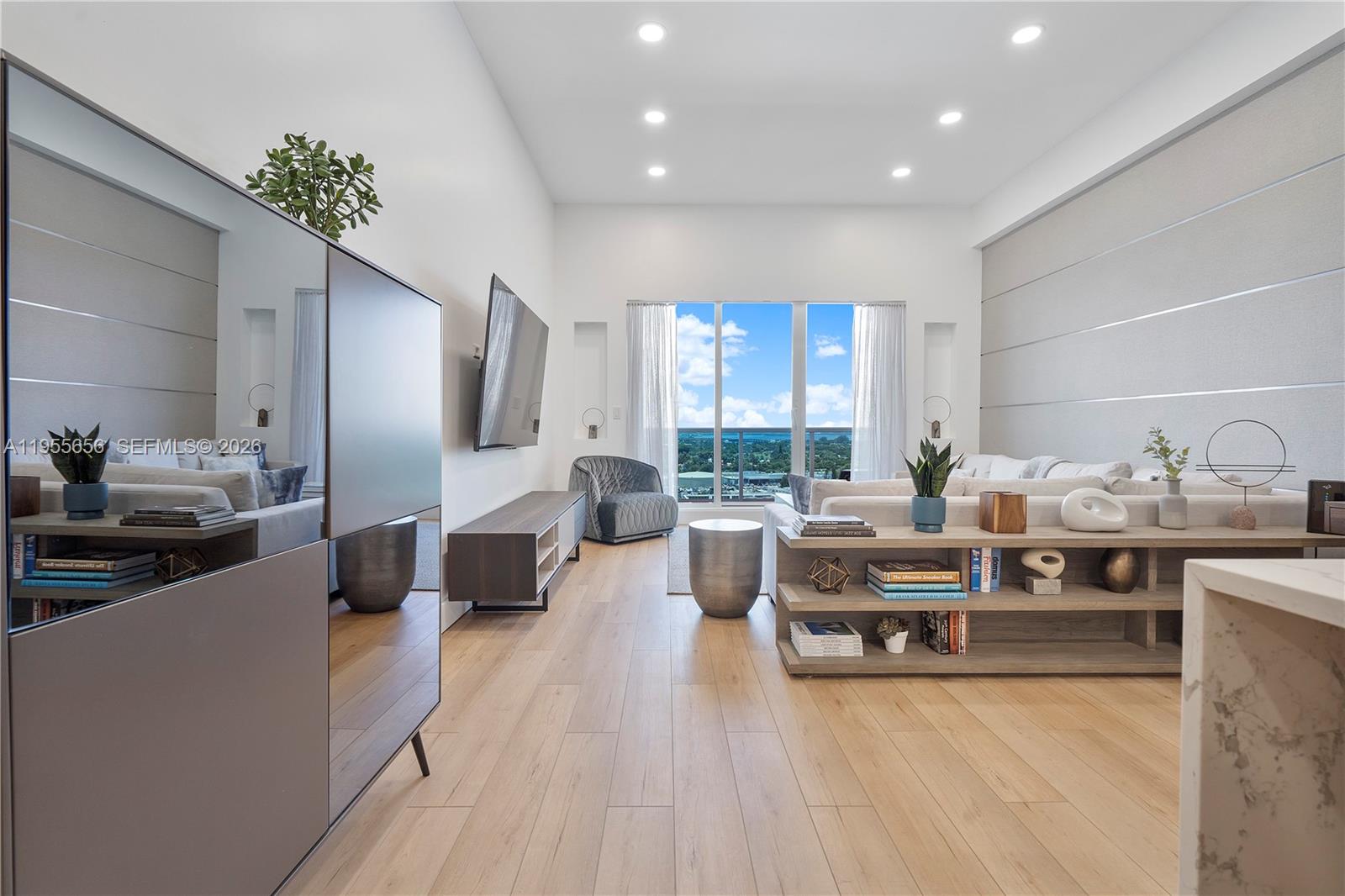 A modern living room features light wood floors, a large window, and a neutral color palette — 2301 Collins Ave # 1633, Miami Beach FL 33139, MIAMI BEACH, FL
