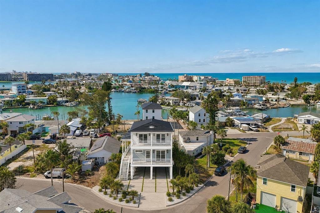 An aerial view of a three-story coastal home with a metal roof and stilt foundation — 13098 BOCA CIEGA AVENUE, MADEIRA BEACH, FL