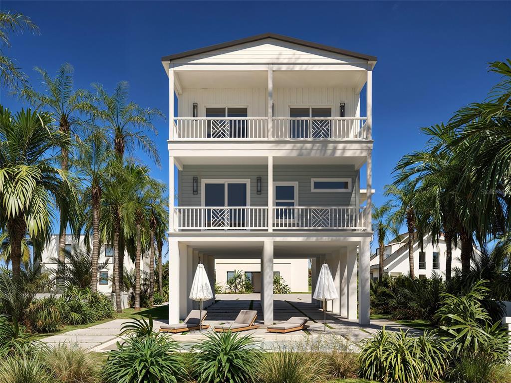 A three-story stilt house with balconies and a ground-level patio featuring lounge chairs and umbrellas — 13098 BOCA CIEGA AVENUE, MADEIRA BEACH, FL