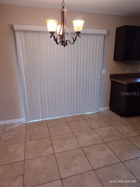 A dining area features tile flooring, a chandelier, and vertical blinds covering a sliding door — 17184 SW 44TH CIRCLE, OCALA, FL
