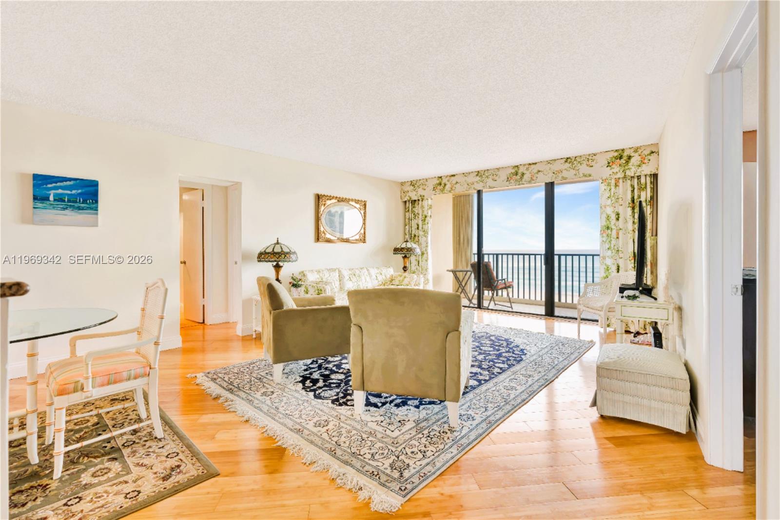 A living room features hardwood floors, a patterned area rug, and a balcony with ocean views — 300 Ocean Trail Way # 1008, Jupiter FL 33477, JUPITER, FL