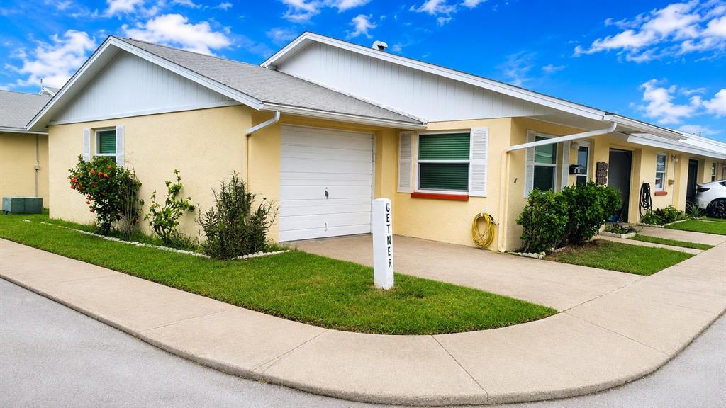 A single-story yellow house with a white garage door and a small front lawn — 4913 GETNER STREET, NEW PORT RICHEY, FL