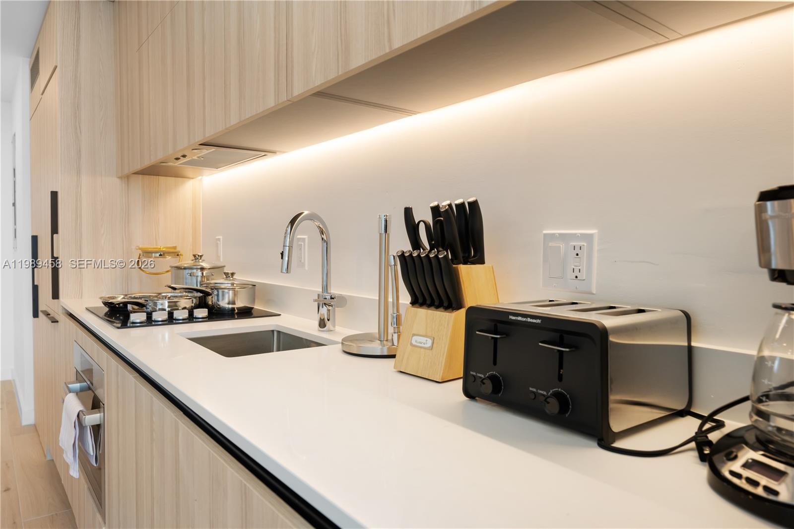 A modern kitchen features light wood cabinets, white countertops, a stainless steel sink, and appliances — 225 N Miami Ave. # 3107, Miami FL 33128, MIAMI, FL