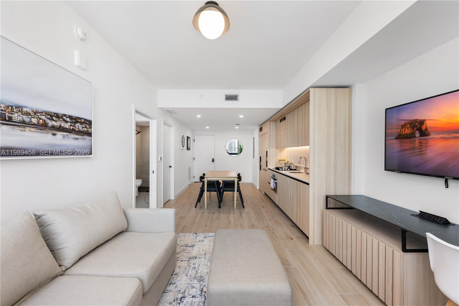 A modern studio apartment features a kitchen, dining area, and living space with light wood floors — 225 N Miami Ave. # 3107, Miami FL 33128, MIAMI, FL