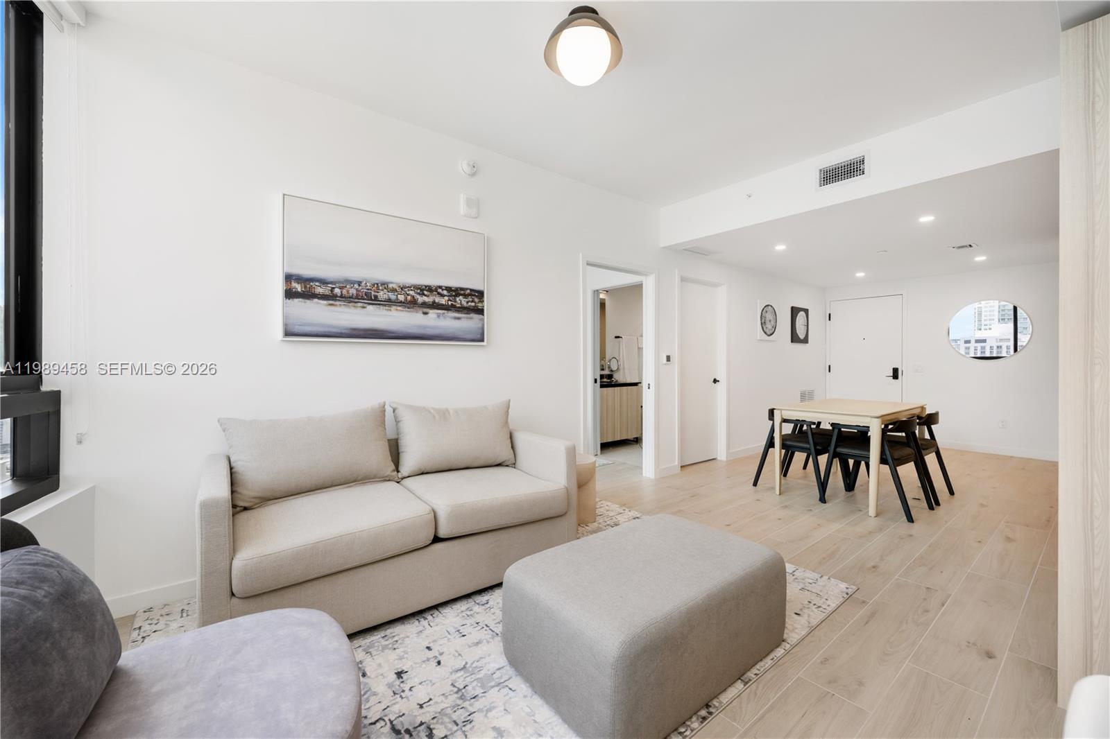 A living and dining area features light wood flooring, a beige sofa, and a dining table — 225 N Miami Ave. # 3107, Miami FL 33128, MIAMI, FL