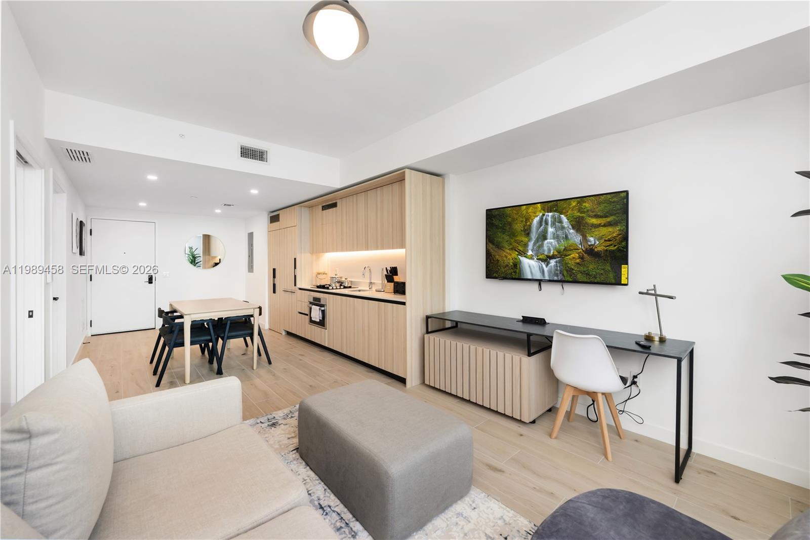 A modern studio apartment features a kitchen, dining area, and living space with light wood — 225 N Miami Ave. # 3107, Miami FL 33128, MIAMI, FL