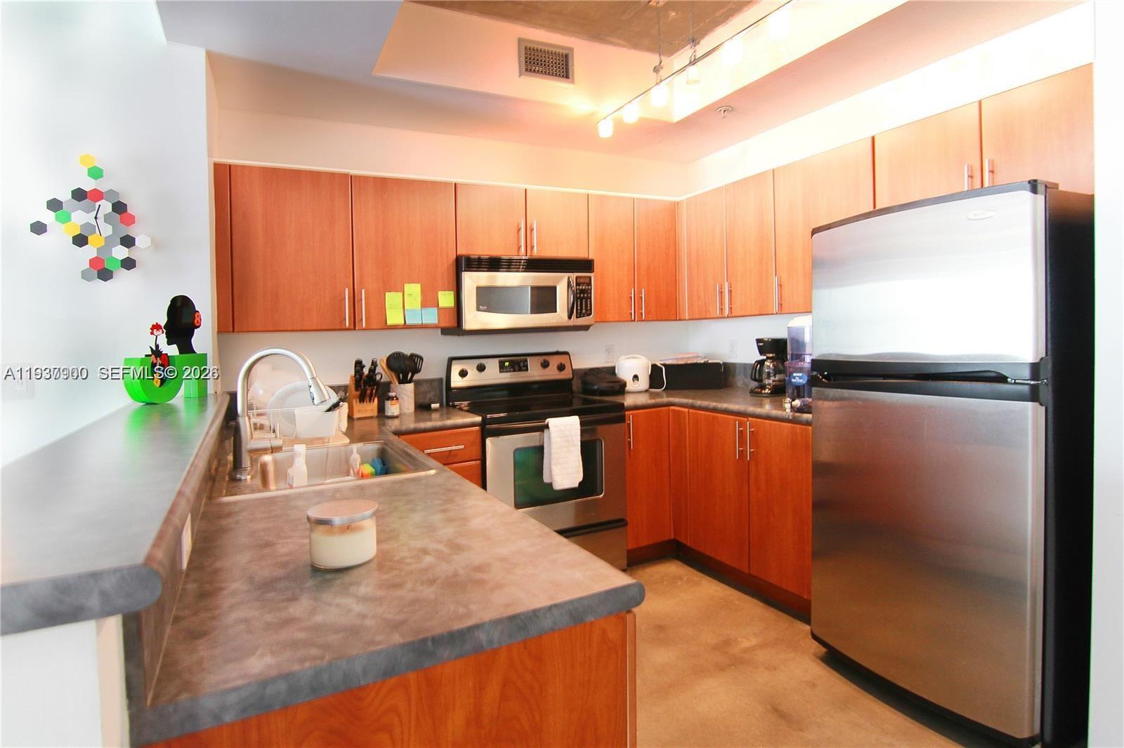 A kitchen features wood cabinets, stainless steel appliances, and a gray countertop — 455 NE 25th St # 407, Miami FL 33137, MIAMI, FL