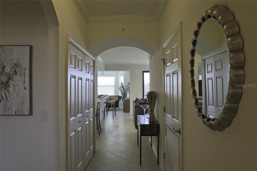A hallway with tile flooring leads through an arched doorway into an open living area — 16804 VARDON TERRACE UNIT 206, LAKEWOOD RANCH, FL