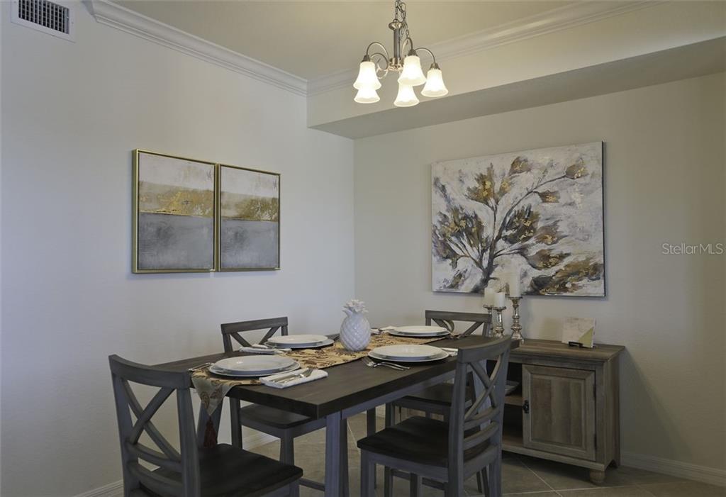 A dining room features a wooden table with four chairs, a sideboard, and wall art — 16804 VARDON TERRACE UNIT 206, LAKEWOOD RANCH, FL