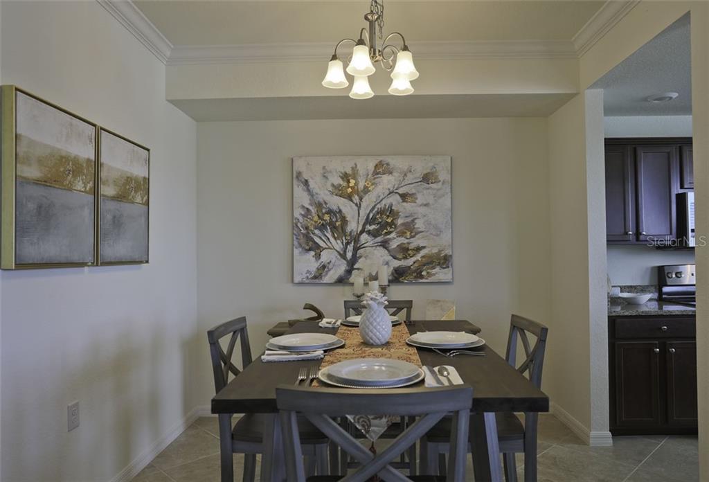 A dining room features a dark wood table, gray chairs, and wall art — 16804 VARDON TERRACE UNIT 206, LAKEWOOD RANCH, FL
