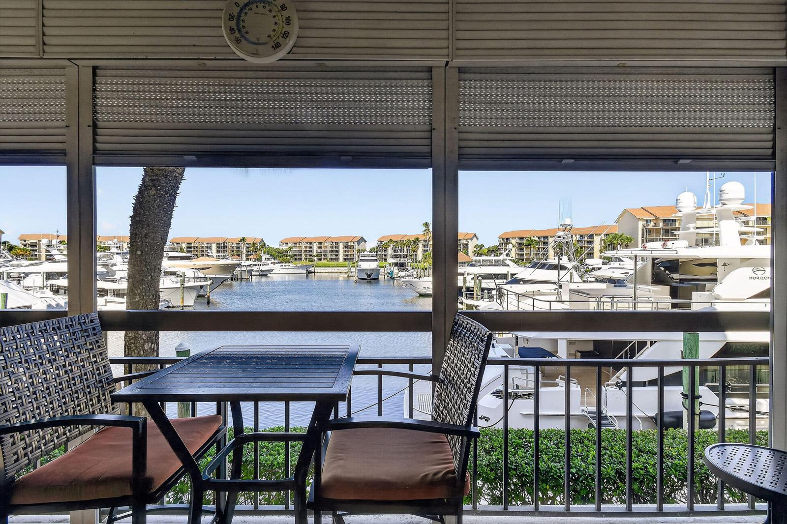 A patio with a table and chairs overlooks a marina filled with docked yachts — 2401 Marina Isle Way # 206, Jupiter FL 33477, JUPITER, FL