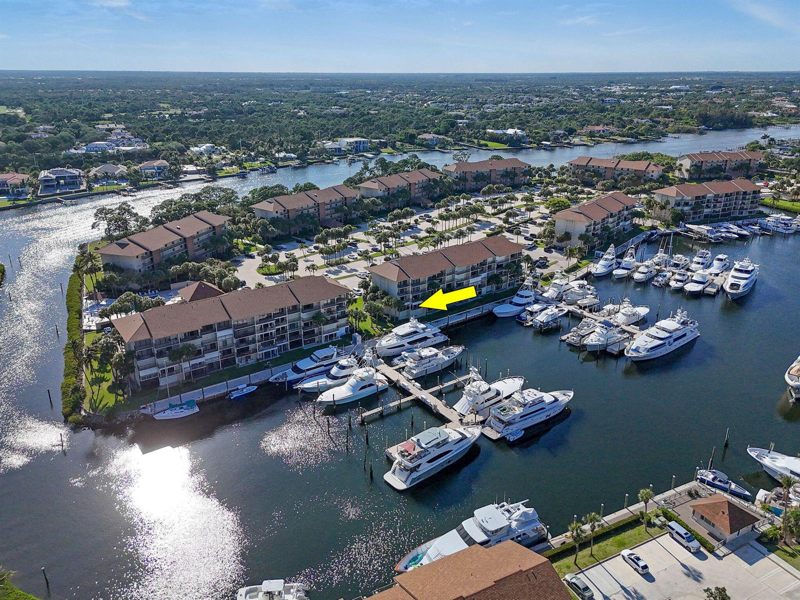 An aerial view shows a multi-story residential building complex situated along a marina with docked yachts — 2401 Marina Isle Way # 206, Jupiter FL 33477, JUPITER, FL