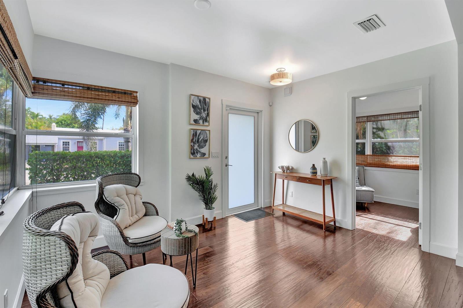 A sunlit entryway features hardwood floors, two wicker chairs, a console table, and a glass door — 414 NE 7th Avenue, Delray Beach FL 33483, DELRAY BEACH, FL