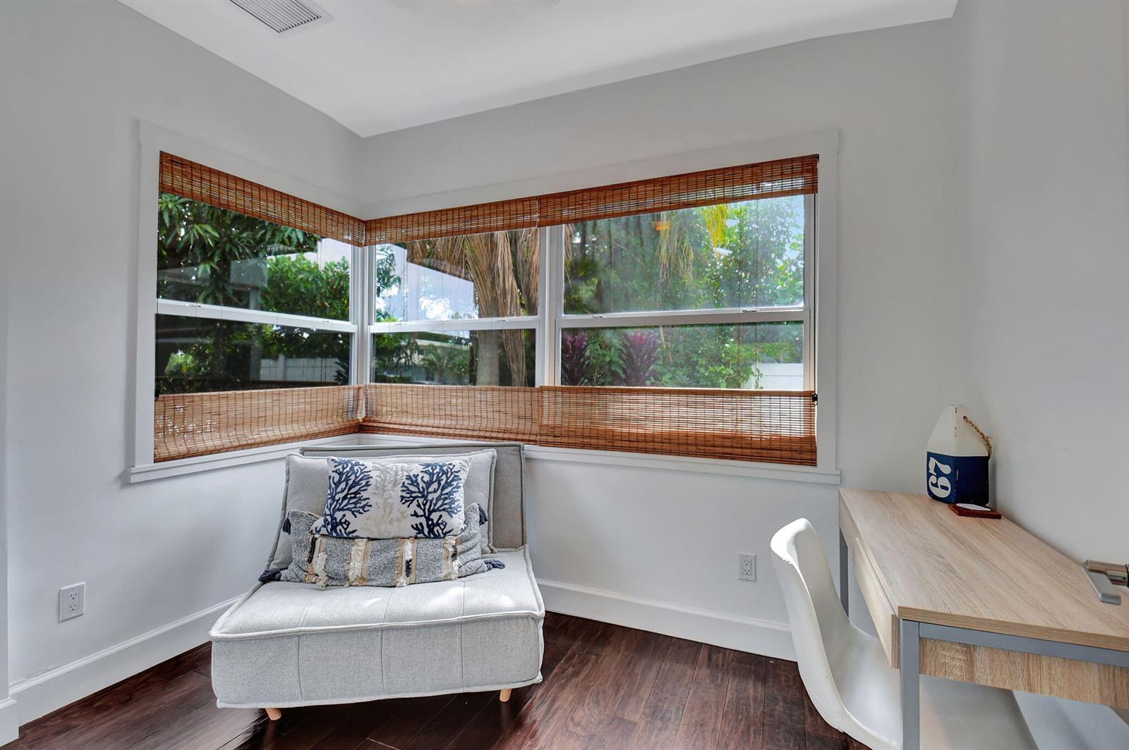 A corner room features a gray chair, a wooden desk, and windows with bamboo shades — 414 NE 7th Avenue, Delray Beach FL 33483, DELRAY BEACH, FL
