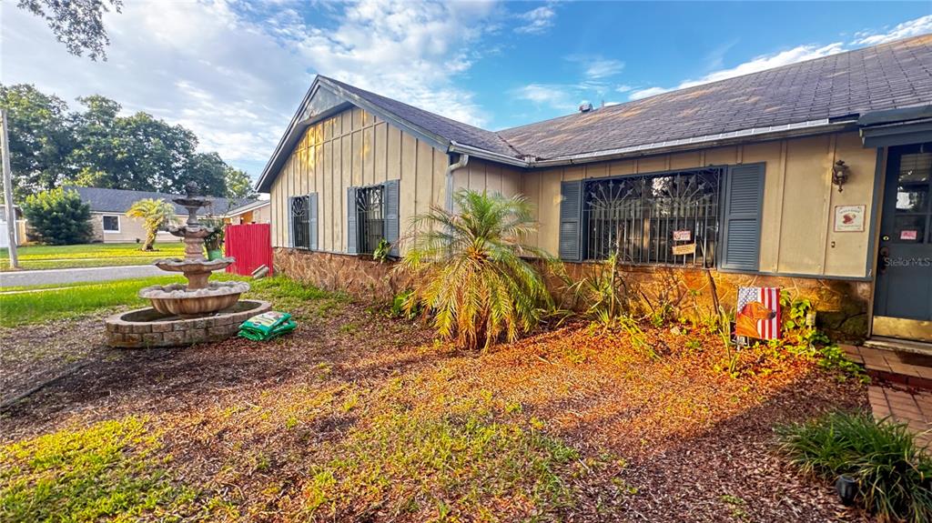 The exterior of a tan house features a stone base, a tiered fountain, and shutters — 8168 STRADA DRIVE, ORLANDO, FL