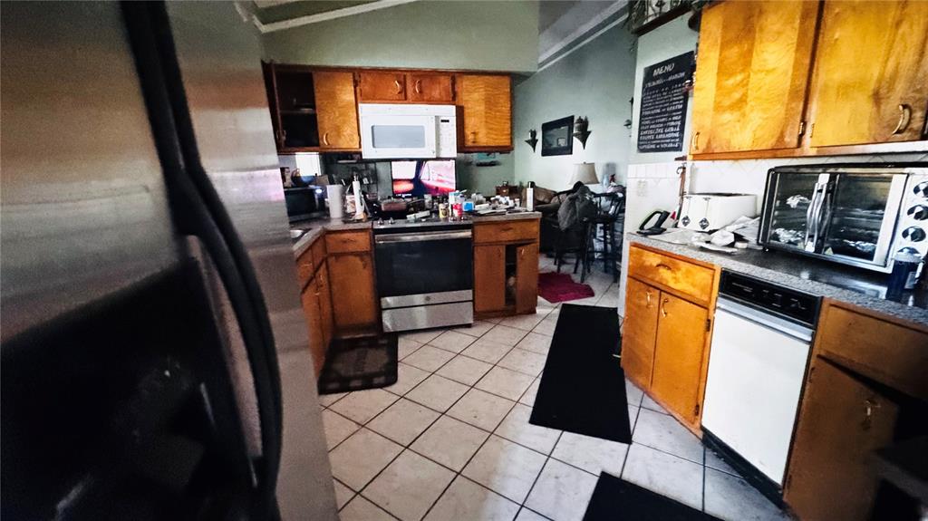A kitchen features wood cabinets, stainless steel appliances, and light-colored tile flooring — 8168 STRADA DRIVE, ORLANDO, FL