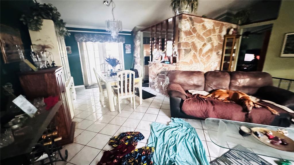 A living room and dining area with tile floors, a stone wall, and a sofa — 8168 STRADA DRIVE, ORLANDO, FL