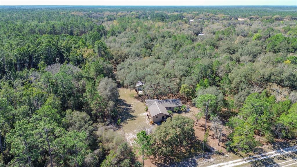 An aerial view shows a single-story house surrounded by dense woods and a dirt driveway — 13455 NE 228TH LANE ROAD, FORT MC COY, FL