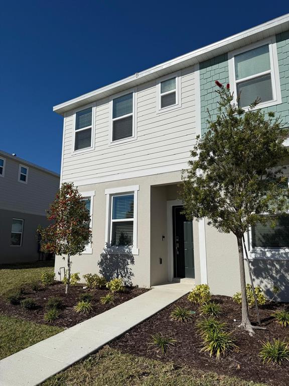 A two-story house exterior features light-colored siding, a front walkway, and two small trees — 3208 SKYLINE LOOP, KISSIMMEE, FL