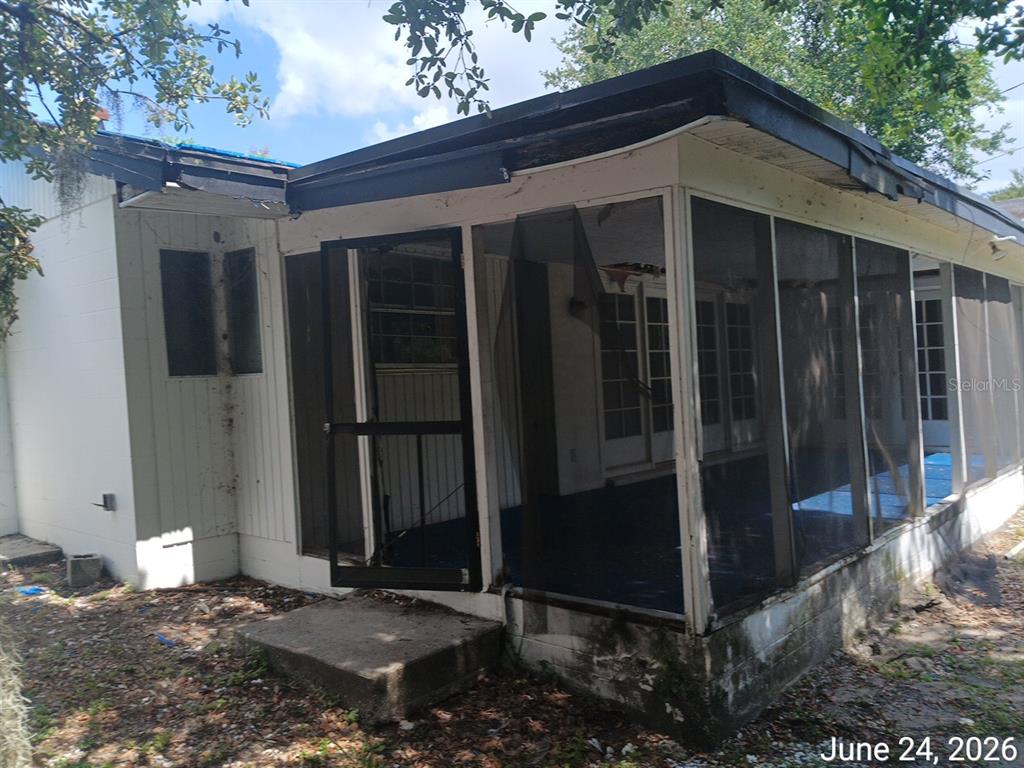 A screened-in porch with a concrete step and white siding attached to a house — 7203 N 41ST STREET, TAMPA, FL
