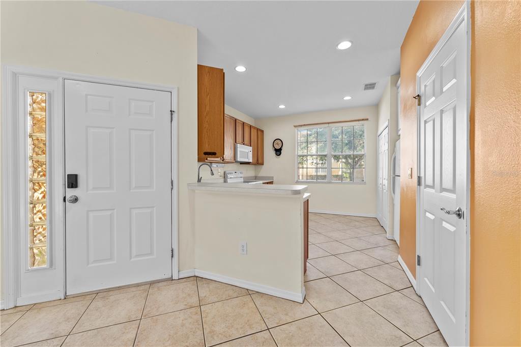 A kitchen with tile flooring, wood cabinets, and a breakfast bar opens to a dining area — 1938 FIESTA RIDGE COURT, TAMPA, FL