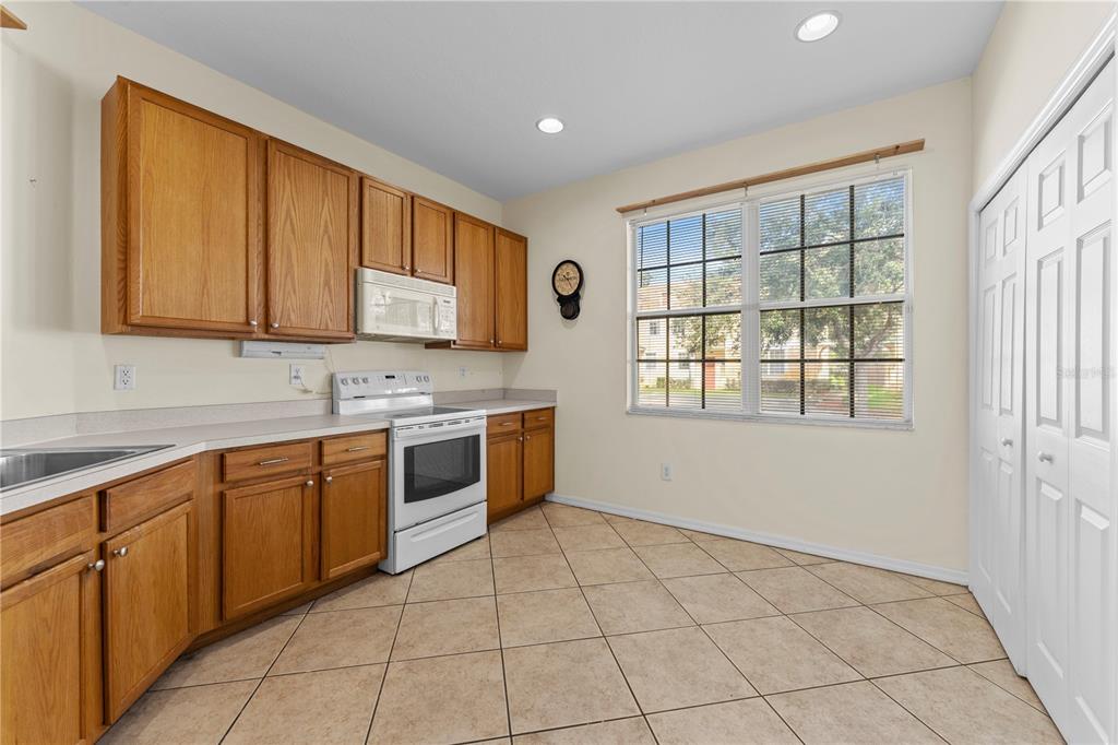 A kitchen with oak cabinets, white appliances, tile flooring, and a large window — 1938 FIESTA RIDGE COURT, TAMPA, FL