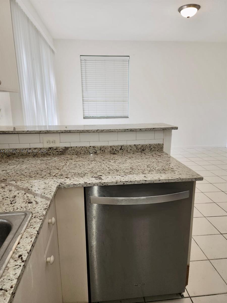 A kitchen features granite countertops, a stainless steel dishwasher, and white subway tile backsplash — HOMESTEAD, FL
