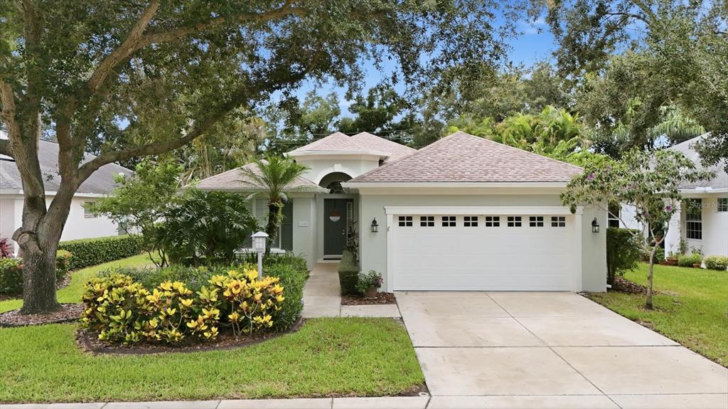 A single-story house with a light green exterior, a two-car garage, and a landscaped front yard — 5540 SIMONTON STREET, BRADENTON, FL