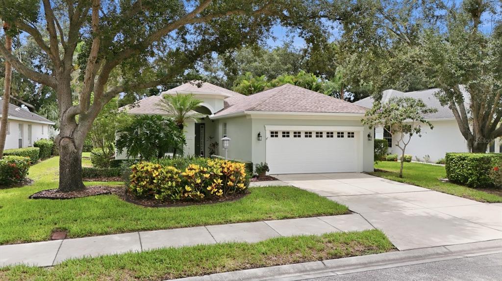 A light green single-story house with a two-car garage and mature landscaping — 5540 SIMONTON STREET, BRADENTON, FL