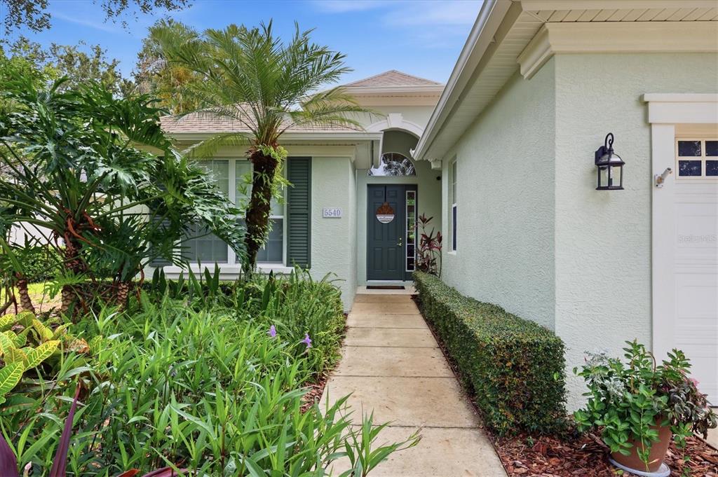 The exterior of a light green house features a walkway leading to a dark front door — 5540 SIMONTON STREET, BRADENTON, FL