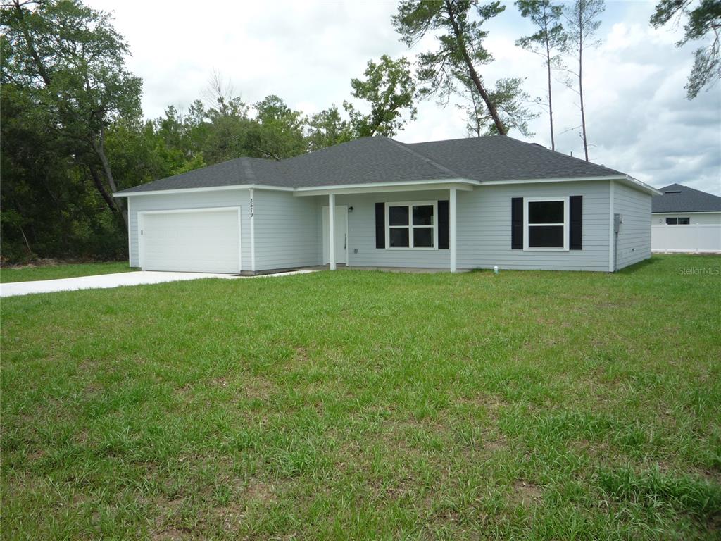 A single-story house with light gray siding, a white garage door, and black window shutters — 3579 SW 128TH PL, OCALA, FL