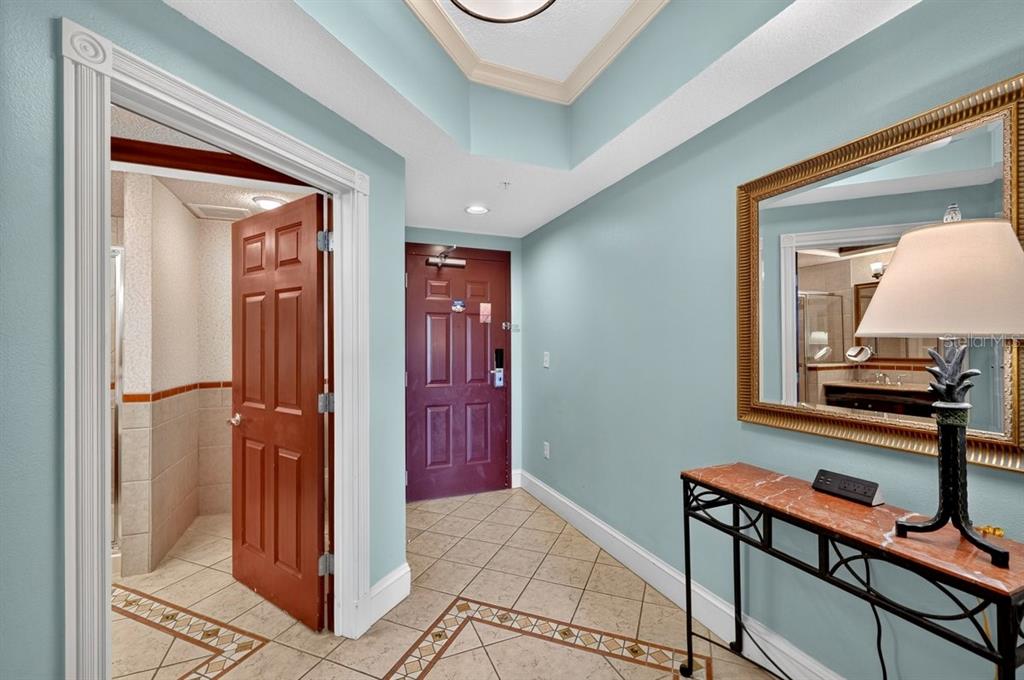 An entryway features light blue walls, tile flooring, a dark wood door, and a console table — 200 OCEAN CREST DRIVE UNIT 137, PALM COAST, FL