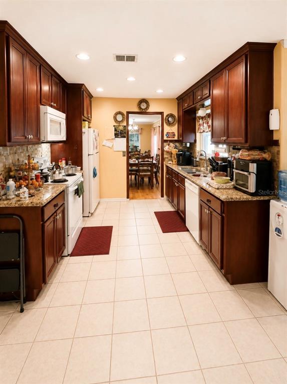 A kitchen with dark wood cabinets, granite countertops, and light tile flooring — 1012 FOREST CIRCLE, WINTER SPRINGS, FL