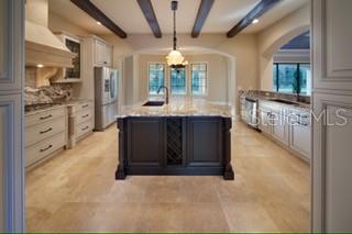 A kitchen features a dark central island, light cabinetry, and wood-beamed ceilings over tile floors — 1657 ENCLAVE COVE, LAKE MARY, FL
