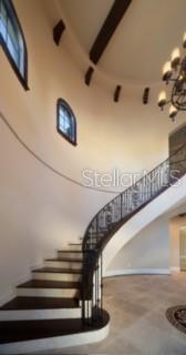 A curved staircase with dark wood steps and a wrought iron railing in a foyer — 1657 ENCLAVE COVE, LAKE MARY, FL