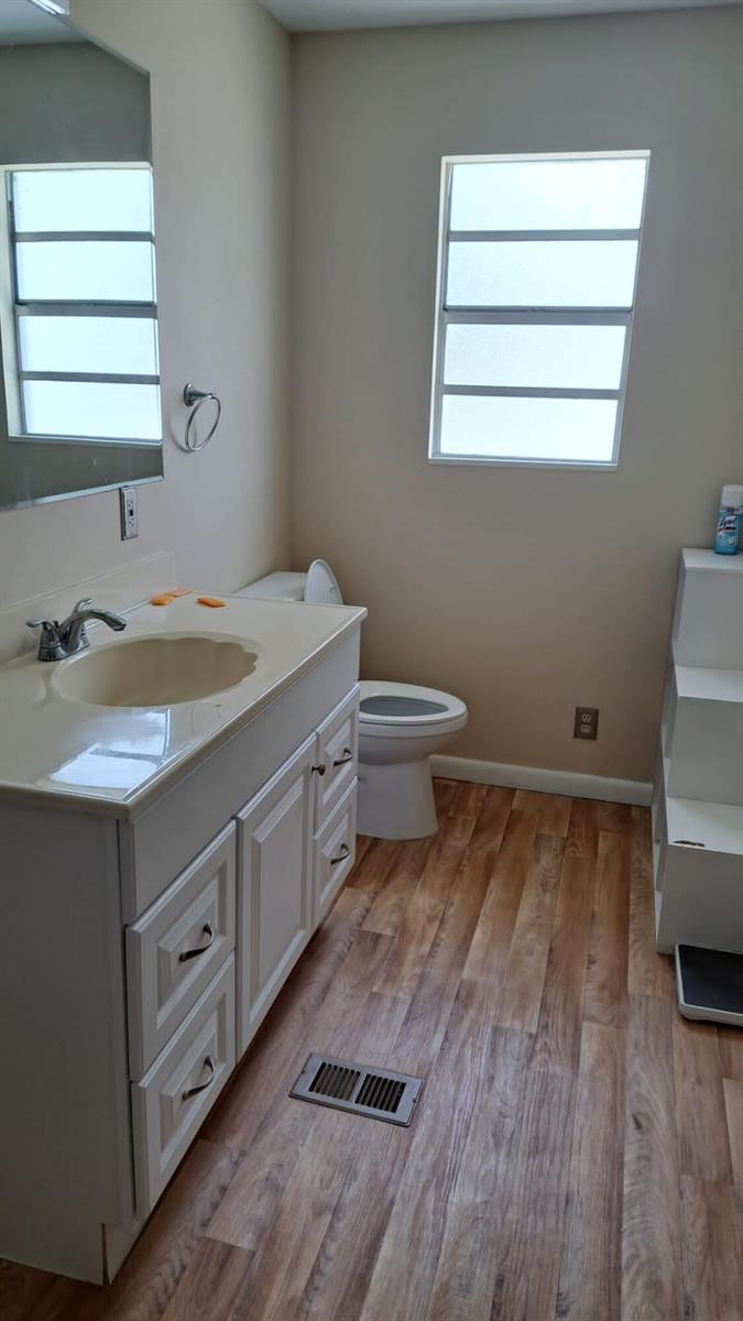 A bathroom features a white vanity with a beige countertop, a toilet, and wood-look flooring — 6275 Us Highway 441 SE, Okeechobee FL 34974, OKEECHOBEE, FL